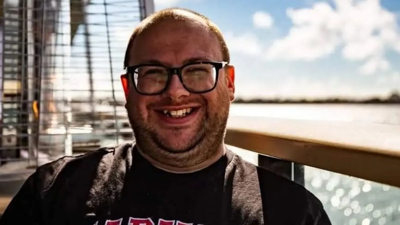 Supplied A man smiling at the camera while on a boat. He is wearing a black t-shirt and dark-rimmed glasses.