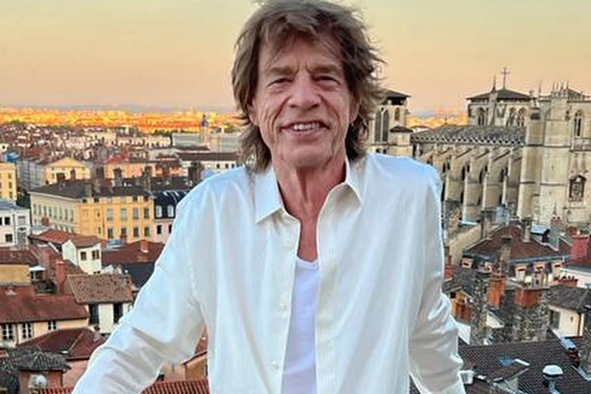 Mick Jagger posa sorridente e de look claro durante uma viagem - Metrópoles