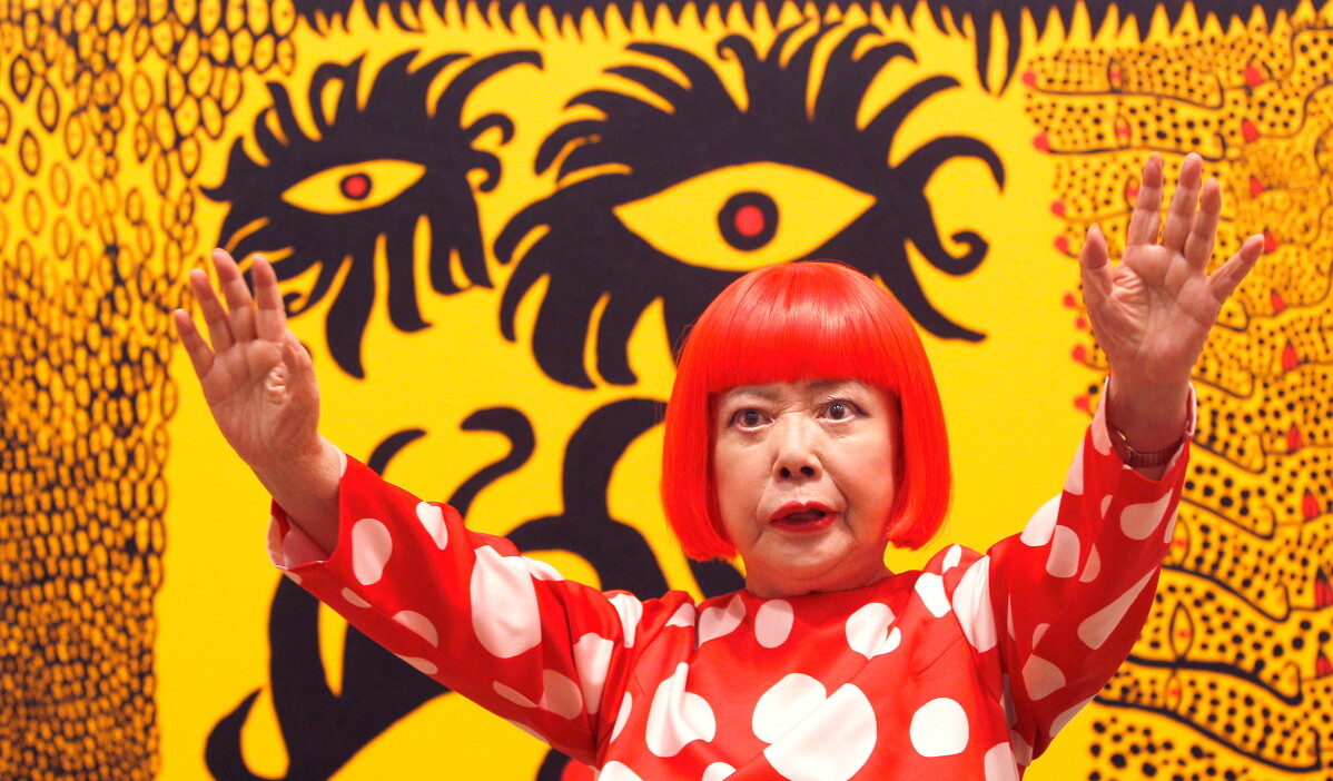 Japanese artist Yayoi Kusama poses for photographers in front of her painting "Love Arrives at the Earth Carrying with it a Tale of the Cosmos" at the Tate Modern in London, on Feb. 7, 2012. (AP Photo/Kirsty Wigglesworth, File)