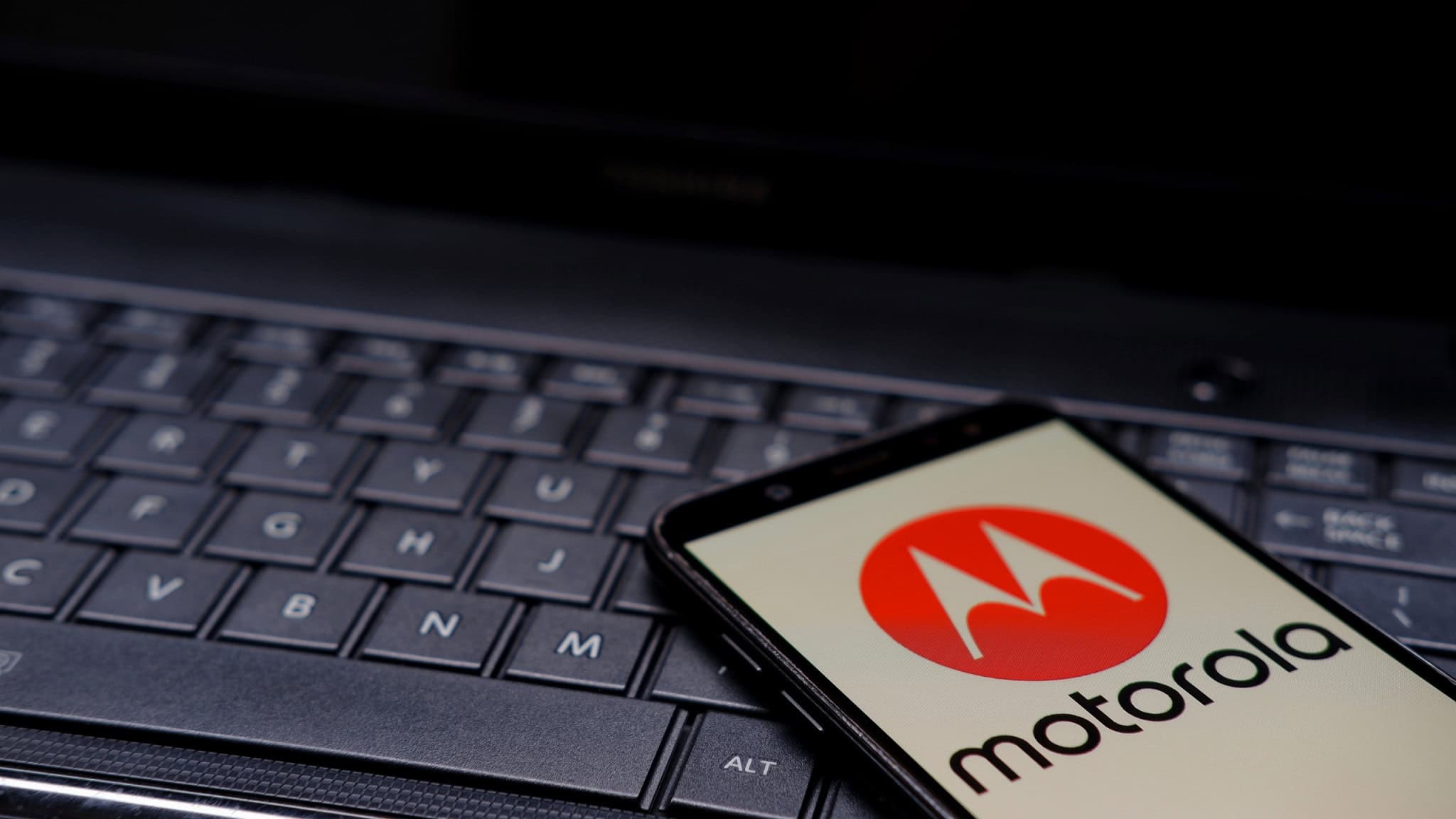 Logo da Motorola em um smartphone, que está em cima de um teclado de notebook